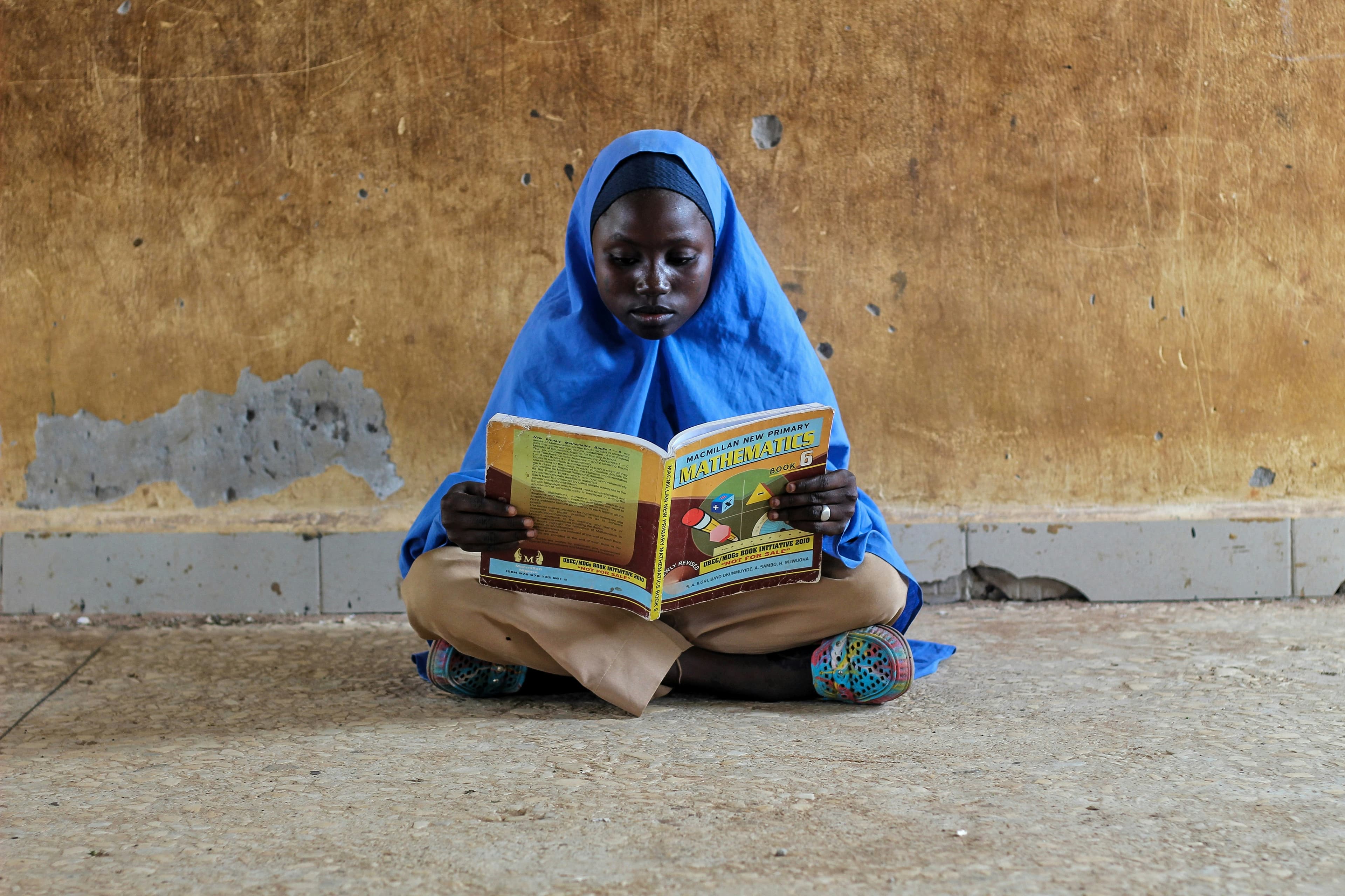 A girl reading a math textbook — clean water unlocks education